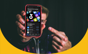 Hombre sosteniendo un teléfono móvil, que muestra en su pantalla iconos de aplicaciones de redes sociales.